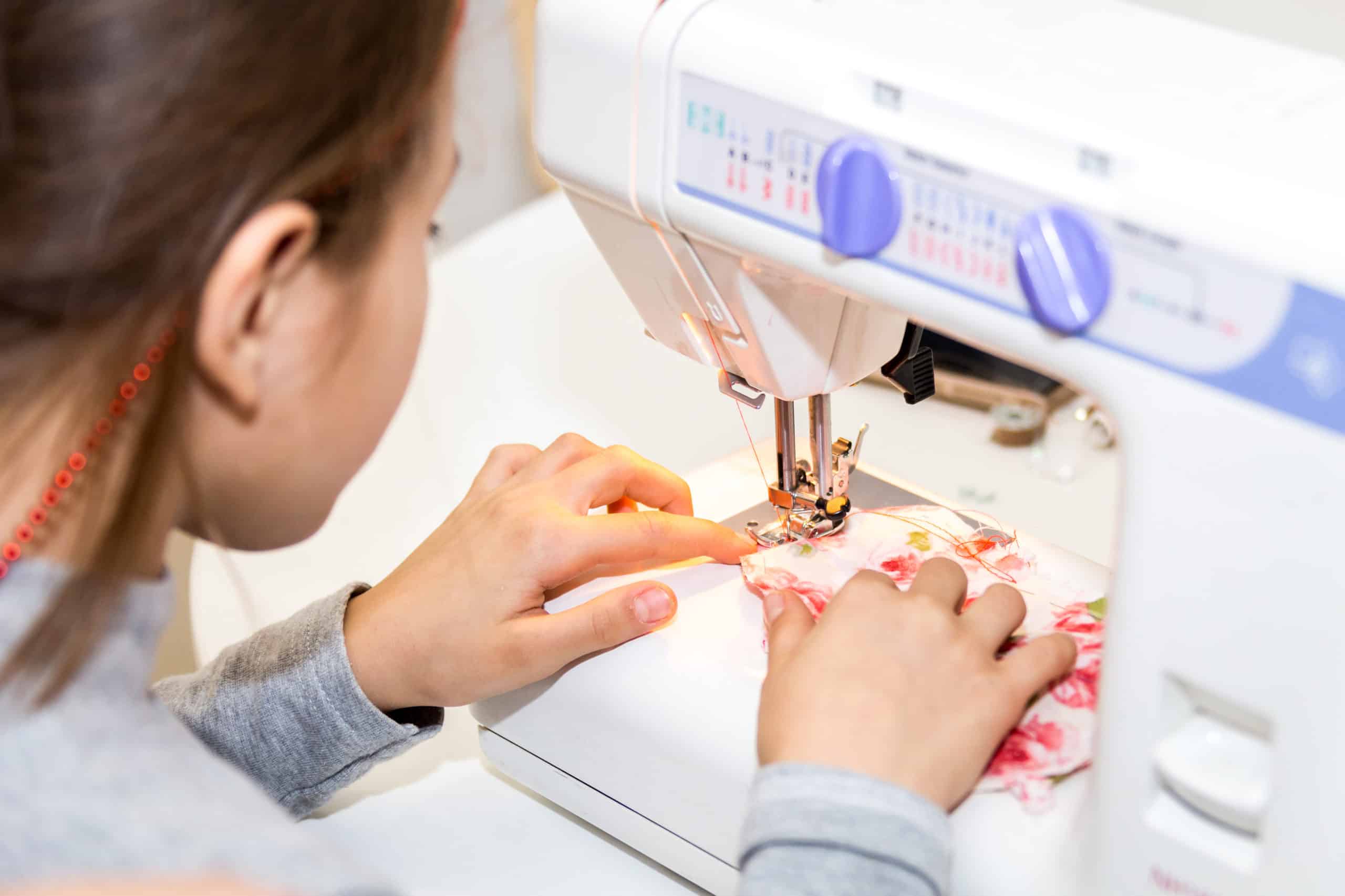 Child operating a sewing machine at sewing camp