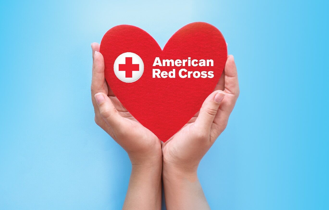 Hands holding felt heart with red cross logo