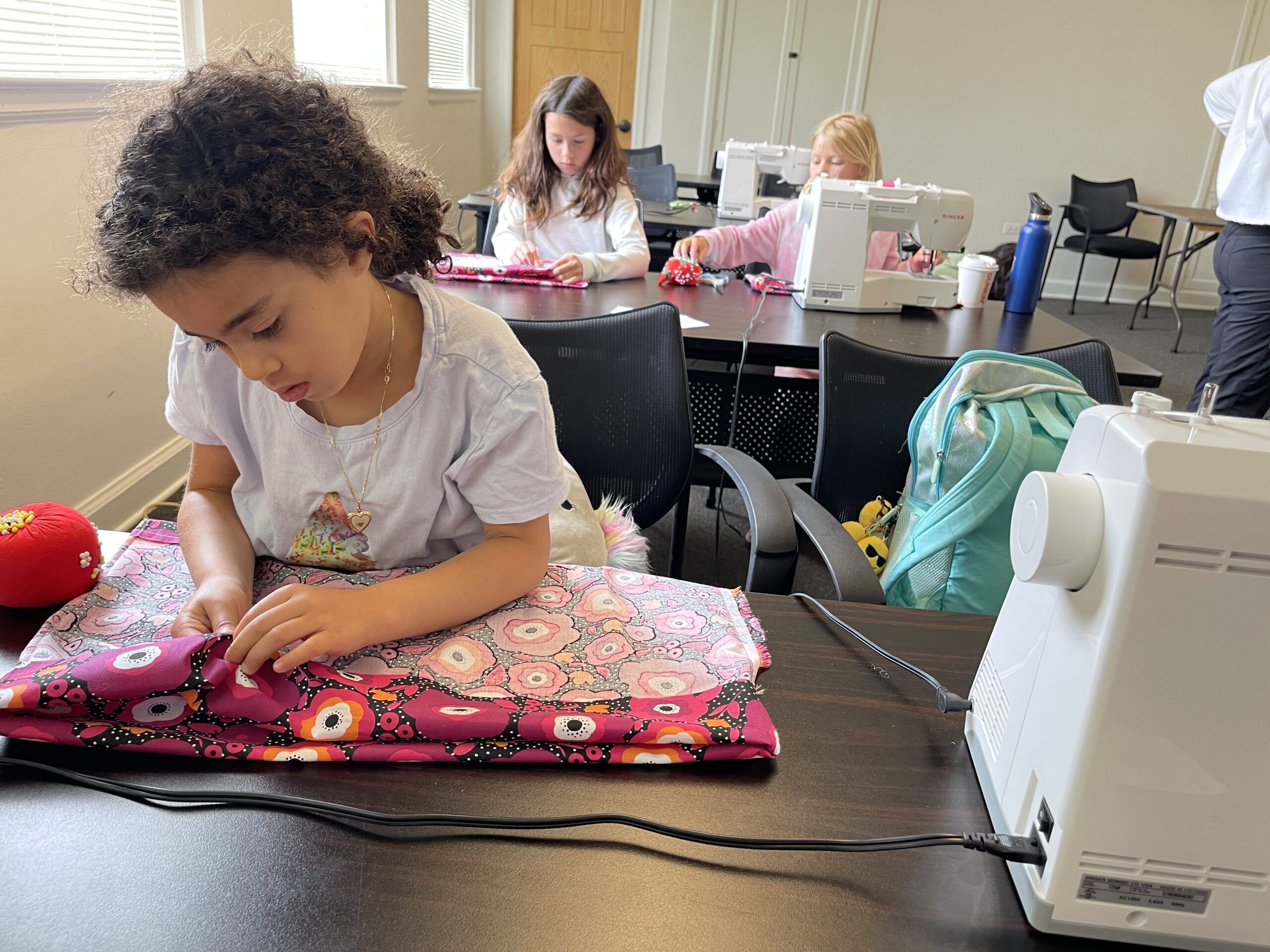 Young girl working at a sewing machine at sewing camp