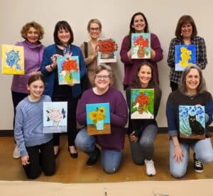 group of women displaying their painting projects