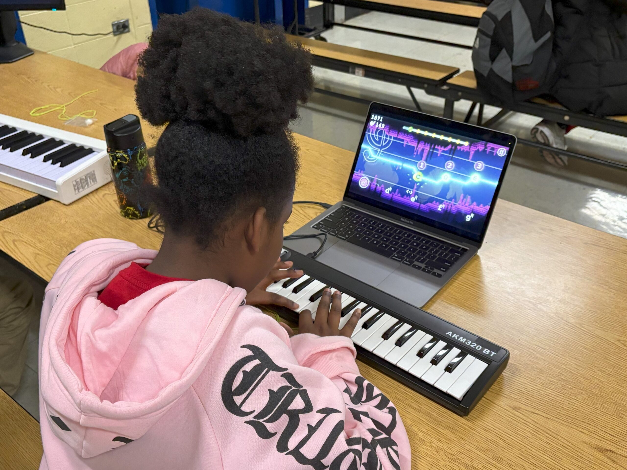 Young girl playing a keyboard attached to a computer at music camp